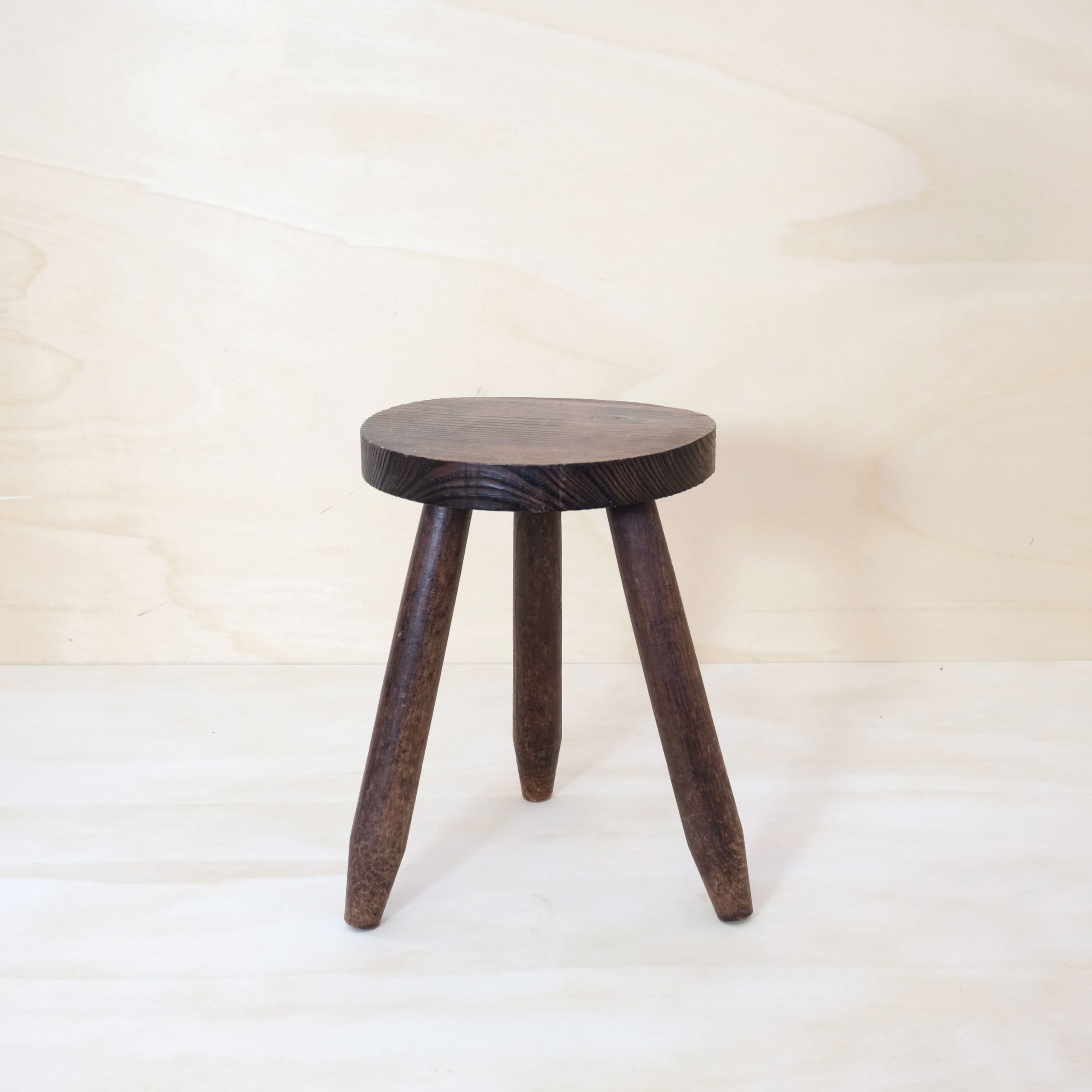 Tripod stool made of wood tinted dark.