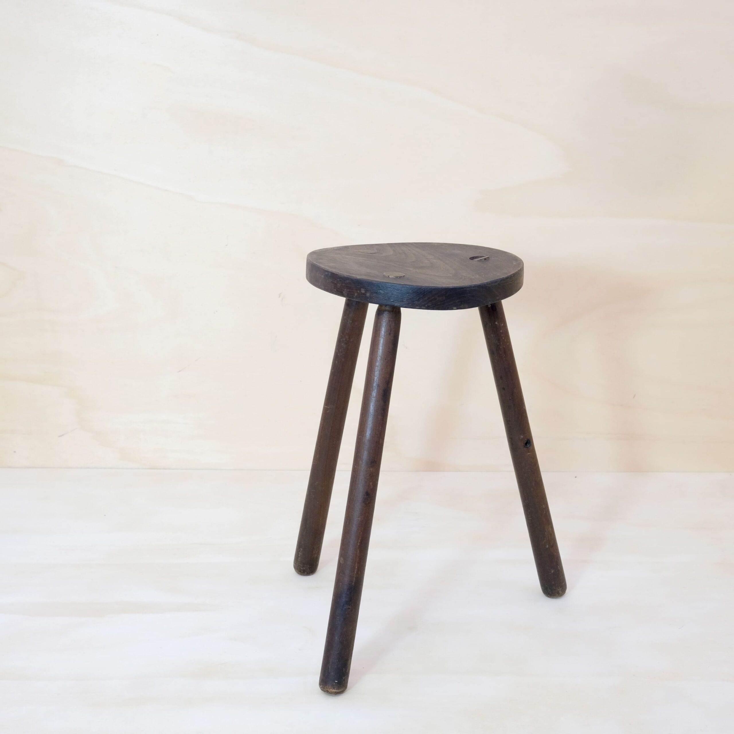 Dark solid wood tripod stool.